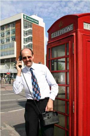 Nigel Linge using a vintage mobile phone and stood outside of a K6 telephone kiosk at the University of Salford, UK